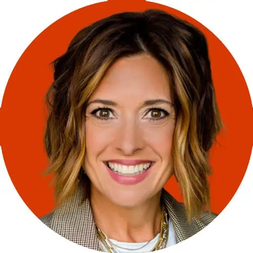 A circular headshot of Cari Kenzie, wearing short, wavy hair smiling in front of an orange background, wearing a checked blazer and white shirt.
